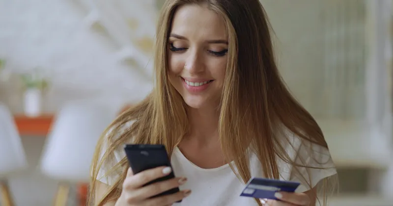 Žena kupuje putem mobitela s bankovnom karticom u ruci